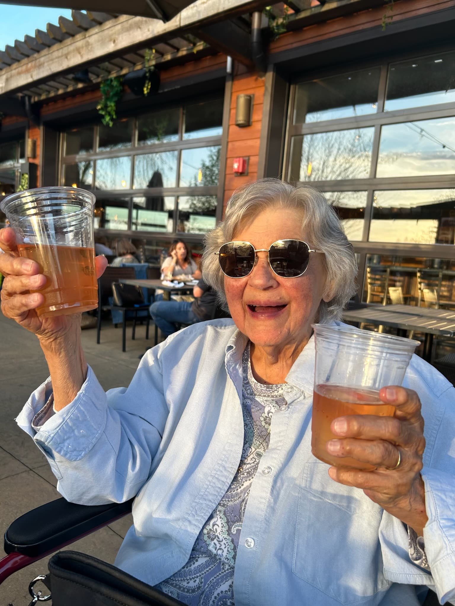 Grandma Mary, toasting the camera with a beer in each hand