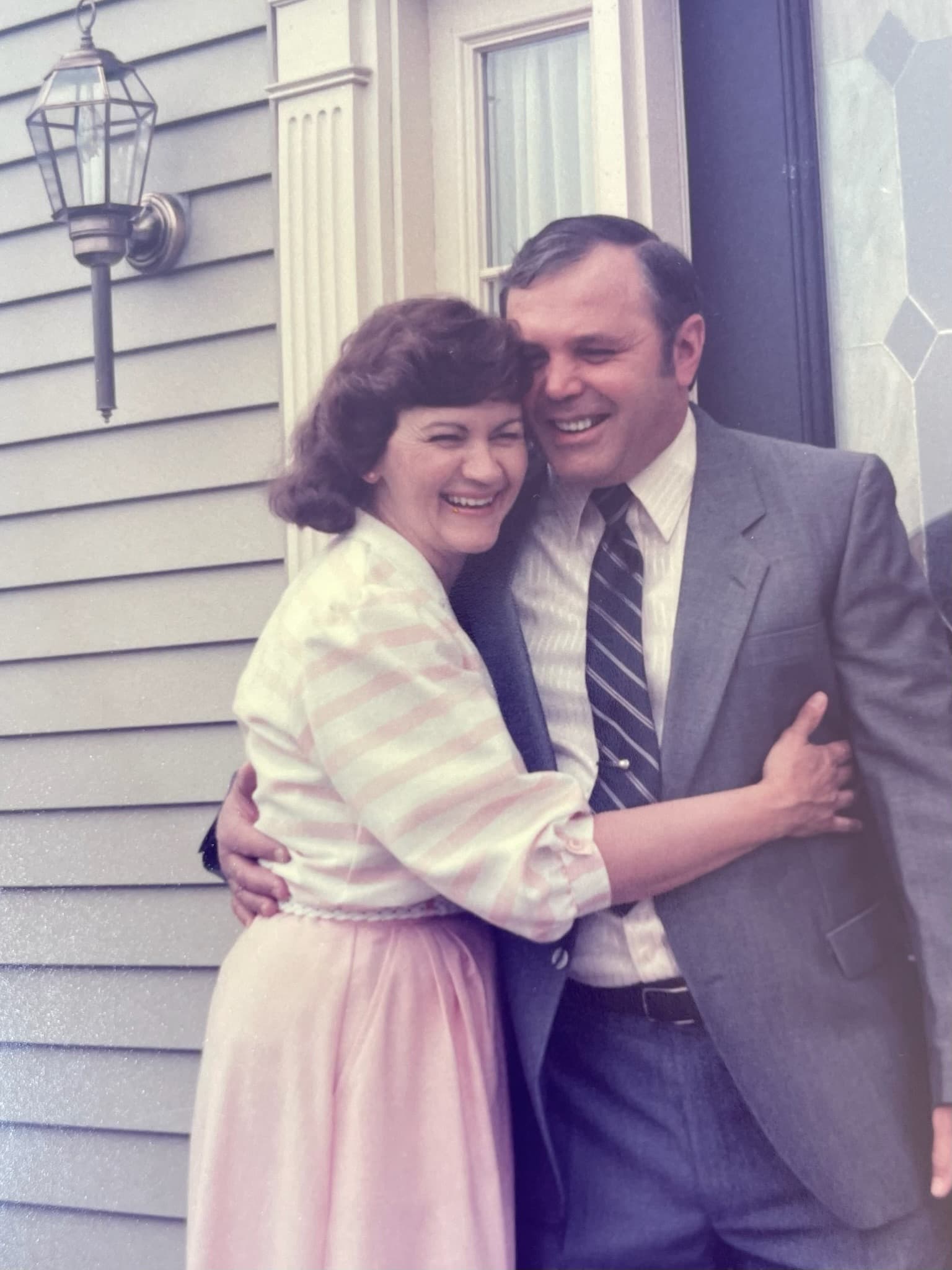 Mary and Gus hugging on their stoop in Solon